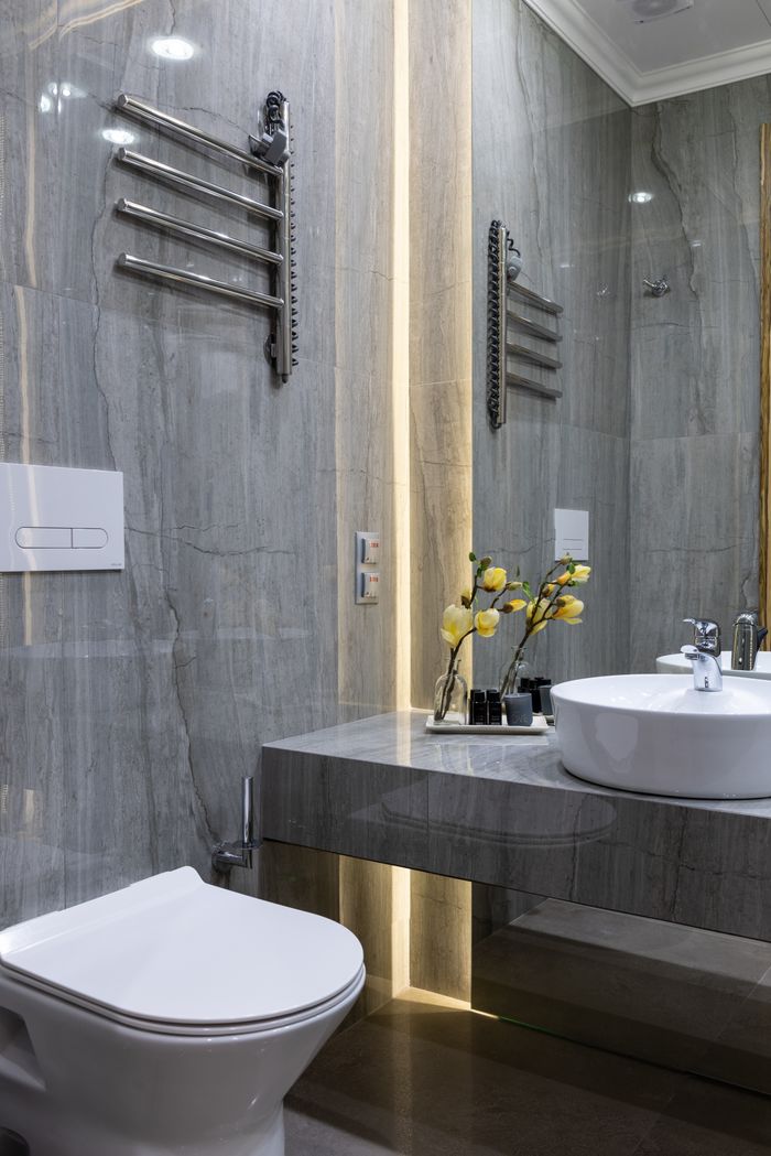services-03 Interior of modern bathroom with sink placed at mirror on marble gray surface with flowers near white ceramic bidet at home